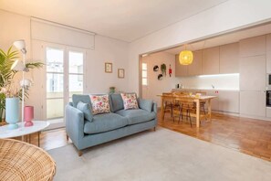 A modern living room with a sofa, dining table, and kitchen area.