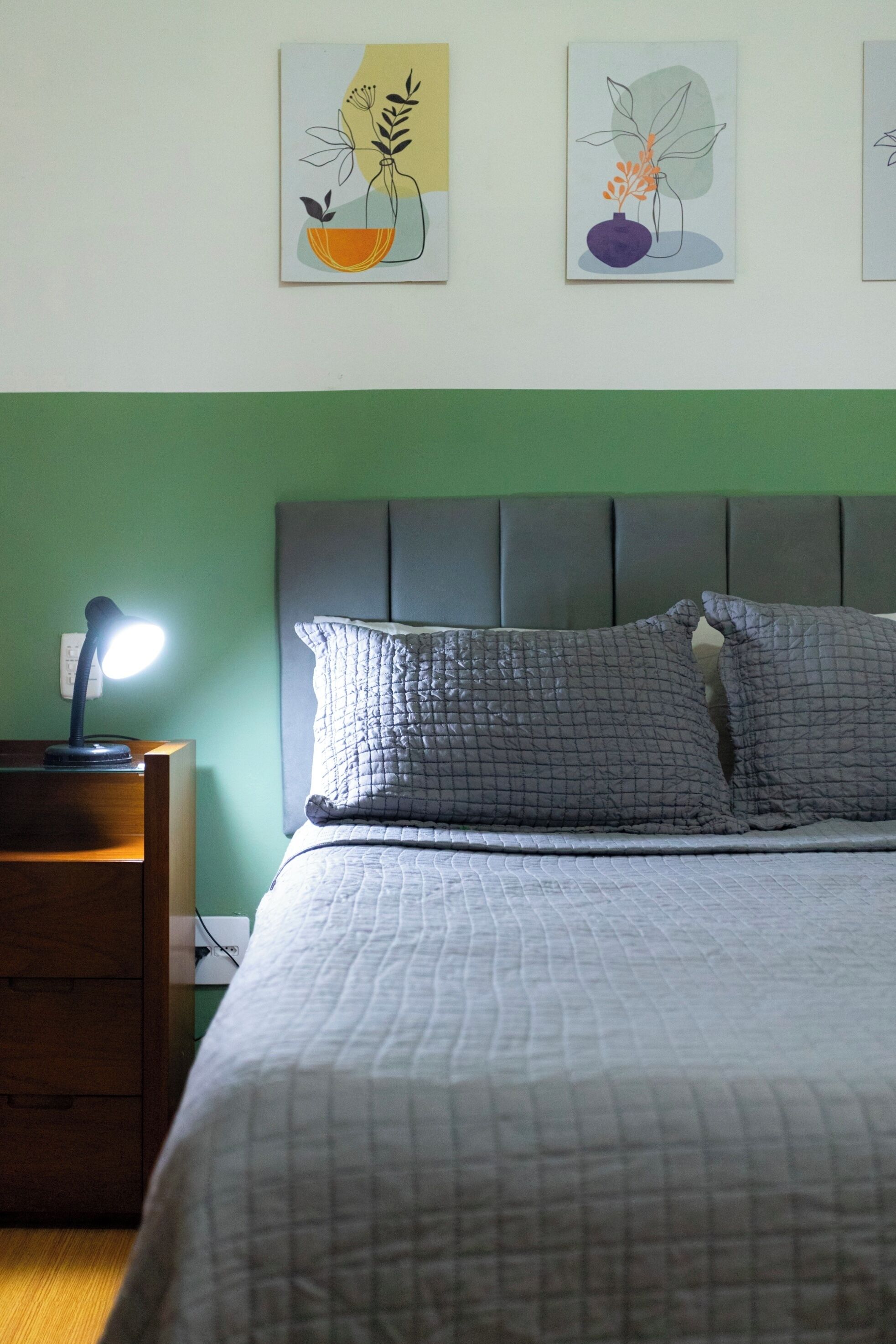 Un lit bien fait, avec une couvre-lit matelassé, une lampe de chevet et deux oreillers.