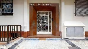 A building entrance with a numbered door, a small step, and a metal gate.