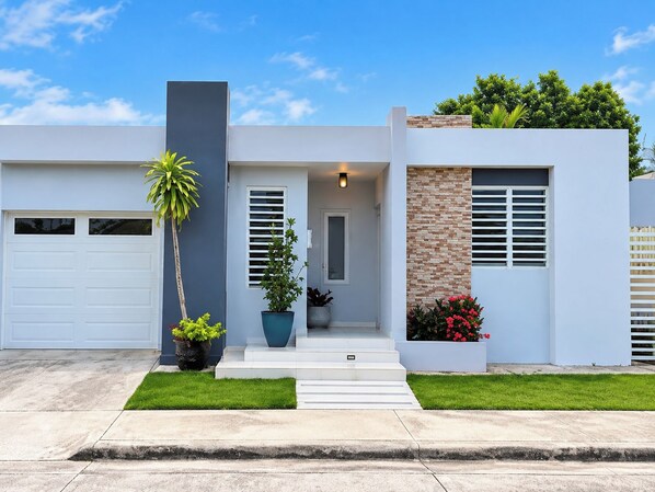 A modern two-story house with a garage, a front porch, and a small garden.
