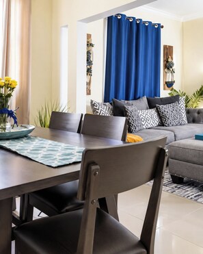 Un salon moderne avec un coin repas, comprenant un ensemble de canapés, une table basse et une table à manger avec des chaises.