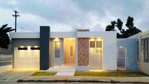 Een modern herenhuis met garage, een gevel van natuursteen en een goed verlichte ingang.