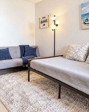 Ein Schlafzimmer mit einem Bett, einer Couch, einem Teppich, einer Stehlampe und Wandkunst.