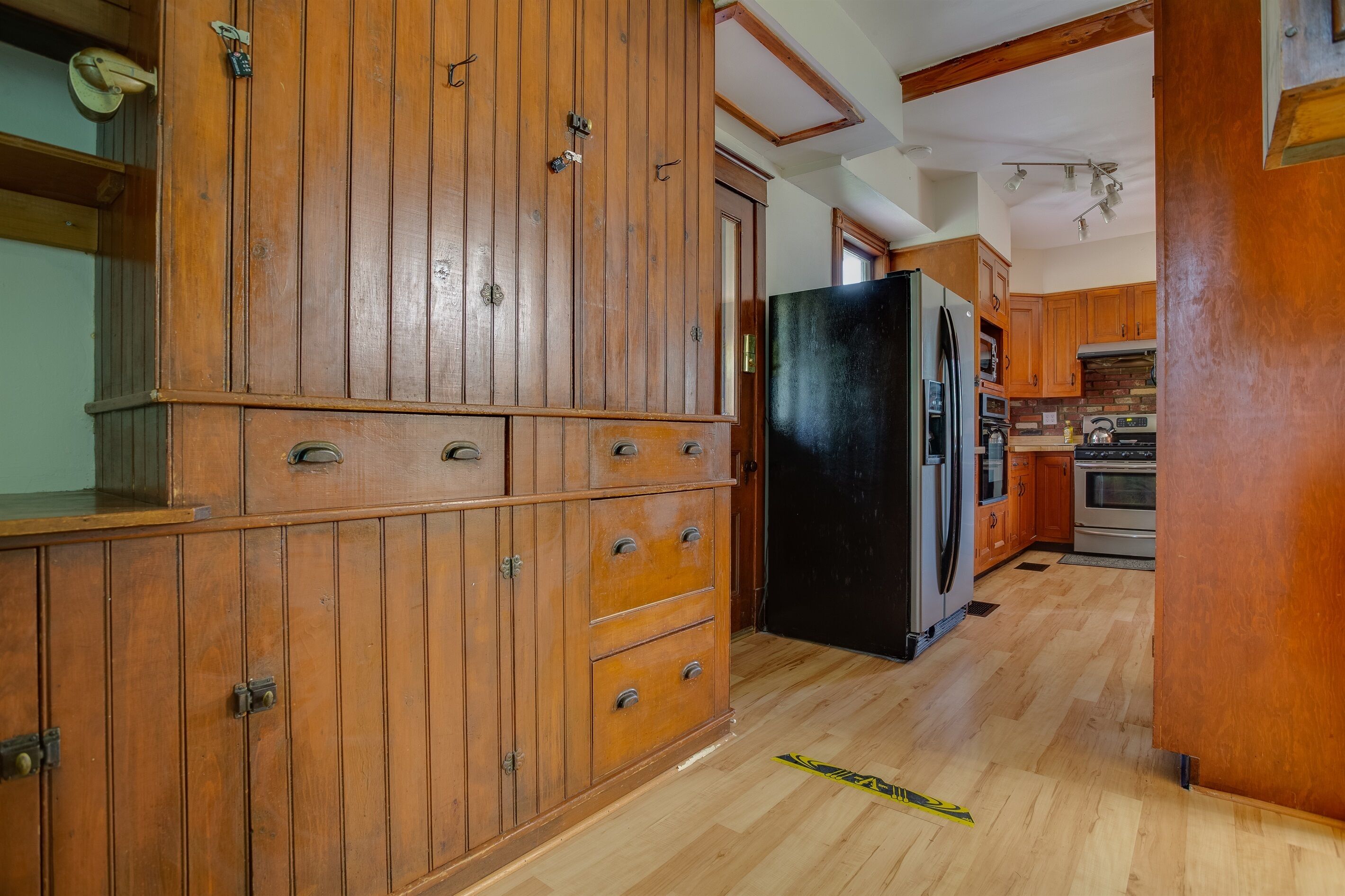 Eine Küche mit Holzschränken, einem schwarzen Kühlschrank und einer Küchenwand aus Ziegelsteinen.