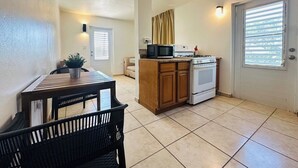 Una cocina compacta con comedor, que incluye un microondas, cocina y una pequeña mesa de comedor con sillas.