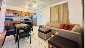 A compact living space with a kitchenette, a dining area with a table and chairs, and a seating area with a sofa and ottoman. - Paradise Beach Apartment Vieques 5 (Vieques)