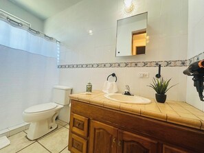Ein Badezimmer mit Toilette, Waschbecken, einem Holzwaschtisch und einer Duschkabine.