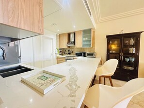 A modern kitchen with a marble countertop, a built-in microwave, a toaster, and a cabinet with glass doors.
