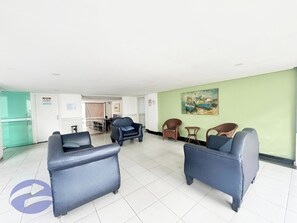 A spacious room with a green wall, a painting, and two blue armchairs.