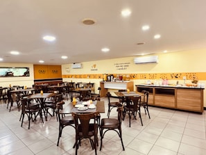 A restaurant with multiple tables and chairs, a buffet counter, and a wall with a mural. -  Ponta Negra Beira Mar - Pimentel (Natal)