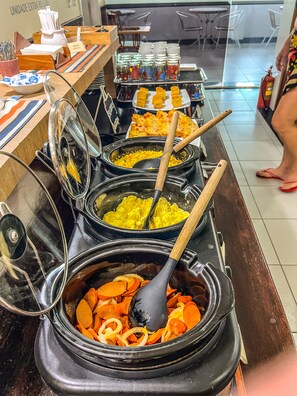 A buffet area with various food items and utensils. -  Ponta Negra Beira Mar - Pimentel (Natal)
