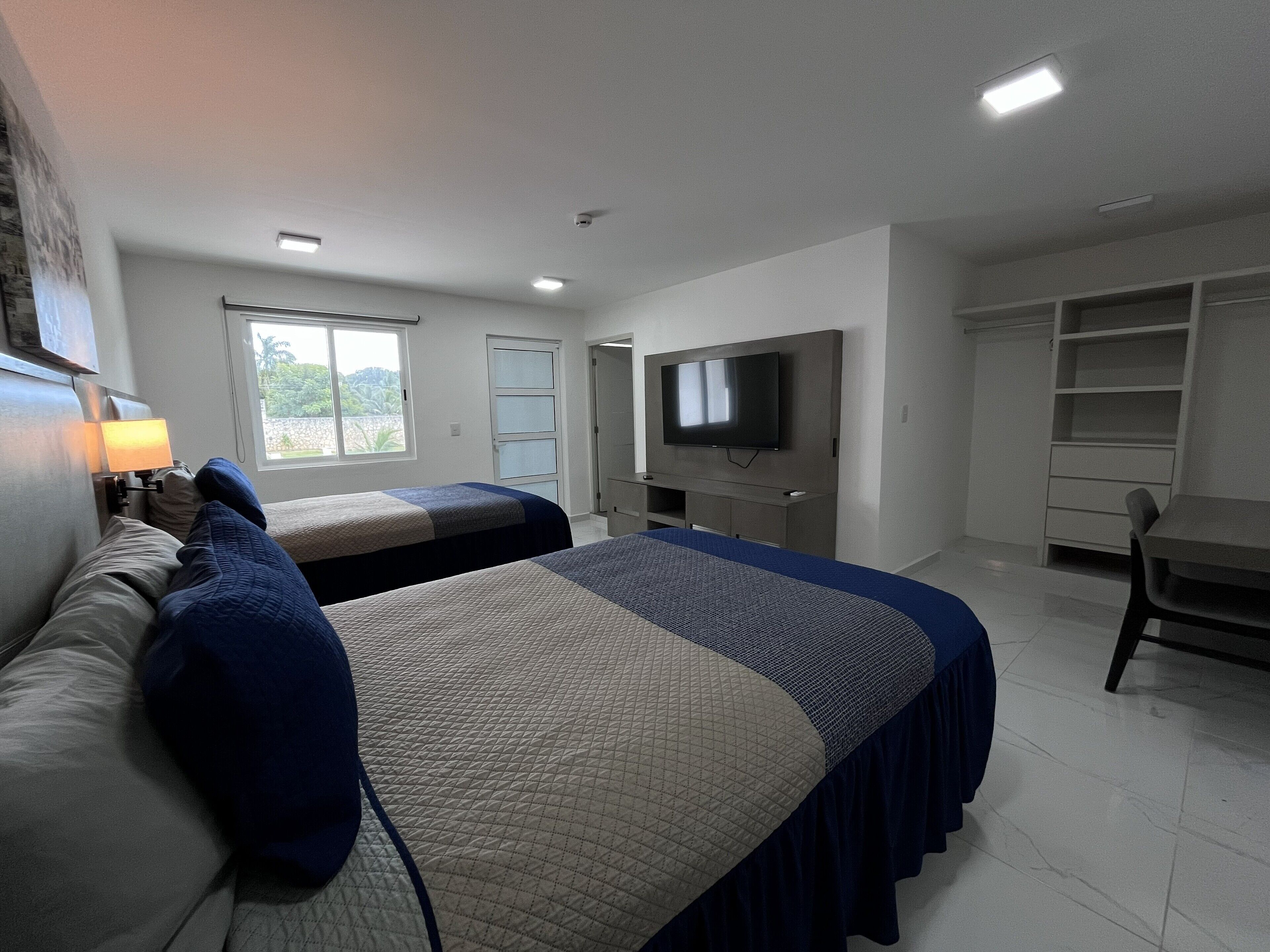 A hotel room with two beds, a TV, a desk, and a wardrobe.