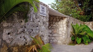 A stone wall with a sign reading 'CASA MURANTA' and a palm tree in the foreground. - Casa Muranta (Cancún)