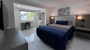 A modern hotel room with a large bed, a desk, and a chair. There is a window providing a view of the outside. - Casa Muranta (Cancún)