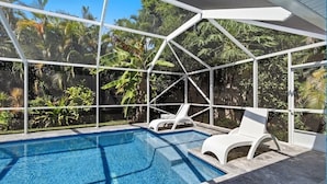 Une piscine à l’eau d’un bleu cristallin, entourée d’une structure en métal blanc.