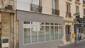 A building with large windows, a visible door, and a small sign on the ground floor. - Newly Renovated ! Stunning 2Br Apt in the Heart of Paris 15 (Paris)