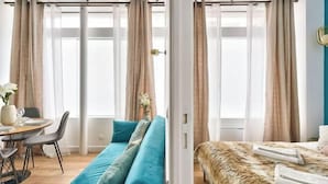 A modern room with a sofa, a bed, a dining area, and large windows with curtains. - Newly Renovated ! Stunning 2Br Apt in the Heart of Paris 15 (Paris)