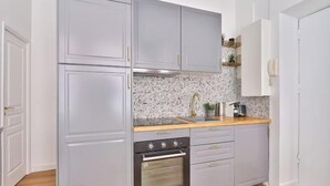 A kitchen with grey cabinets, a wooden countertop, a stainless steel oven, and a backsplash with a speckled pattern. - Newly Renovated ! Stunning 2Br Apt in the Heart of Paris 15 (Paris)
