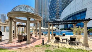 A rooftop pool area with a gazebo, lounge chairs, and a view of modern buildings. - Vogue| Park Tower DIFC near Museum of the Future (Dubai)