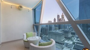 A high-rise room with a panoramic city view, a round glass table, and two wicker chairs with cushions. - Vogue| Park Tower DIFC near Museum of the Future (Dubai)