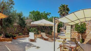 Relax in a serene outdoor space with a covered seating area, potted plants, and a shaded table.