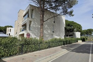 A modern building with a flat facade, a visible balcony, and a tree in front. - Pinegrove Apartment (Durres)