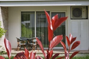 A patio with a table and chairs, a sliding glass door, and an air conditioning unit. - Pinegrove Apartment (Durres)