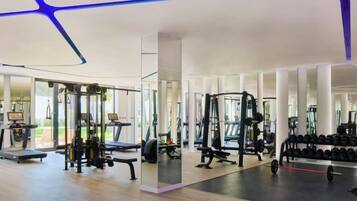 A modern gym with various exercise equipment, large windows, and a clean, open floor plan.