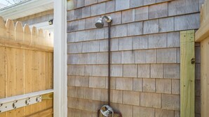 A showerhead mounted on a wooden wall with a metal pipe.