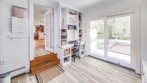 A spacious room with a wooden floor, a desk with a chair, and a large sliding glass door leading to an outdoor area.