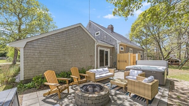 A backyard with a fire pit, outdoor furniture, and a hot tub.