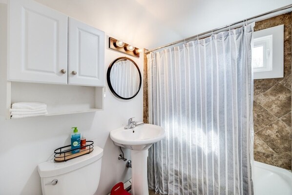 A bathroom with a toilet, sink, and shower curtain.