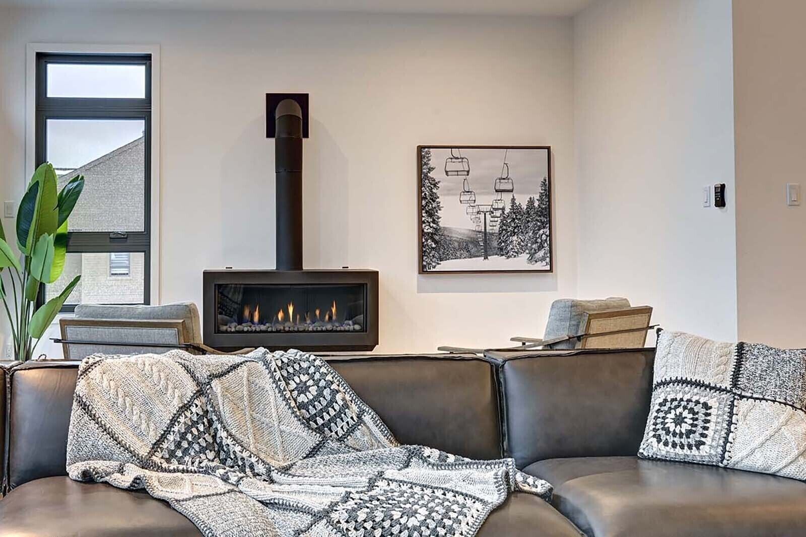 Una sala de estar con chimenea, un sofá, un cuadro enmarcado y un ventanal.