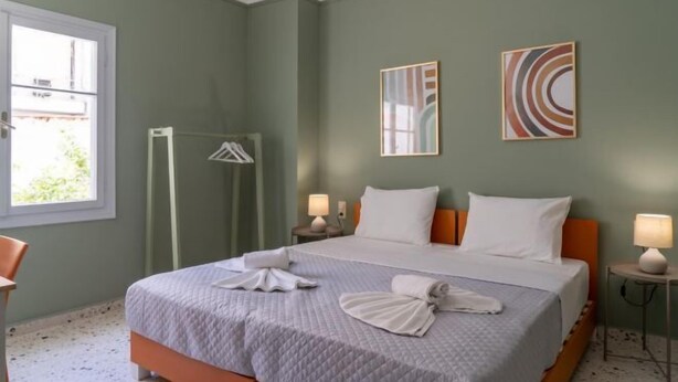 A hotel room with a bed, two bedside lamps, a window, and a wall with abstract art. - Soneto 32 Heraklion House (Heraklion)
