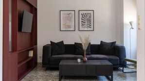 A modern living room with a dark sofa, a coffee table, and two framed artworks on the wall. - Soneto 32 Heraklion House (Heraklion)
