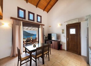 Un espace repas comprenant une table et des chaises, un téléviseur et une vue sur la mer.