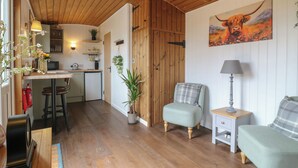 A cozy interior with wooden floors, a kitchen area, and a seating area with a painting of a bull. - The Heron (Cambridge)
