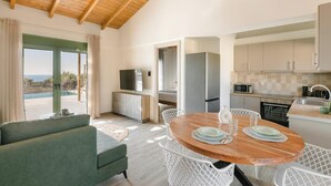 A modern kitchen with a dining area, a TV, and a view of the sea. - Panagis Villa - Three Bedroom Villa, Sleeps 6 (Karavados)