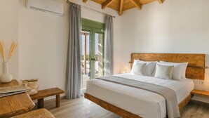 A bedroom with a wooden ceiling, a bed with white bedding, a wooden bench, a bedside table, and a view through a glass door. - Panagis Villa - Three Bedroom Villa, Sleeps 6 (Karavados)