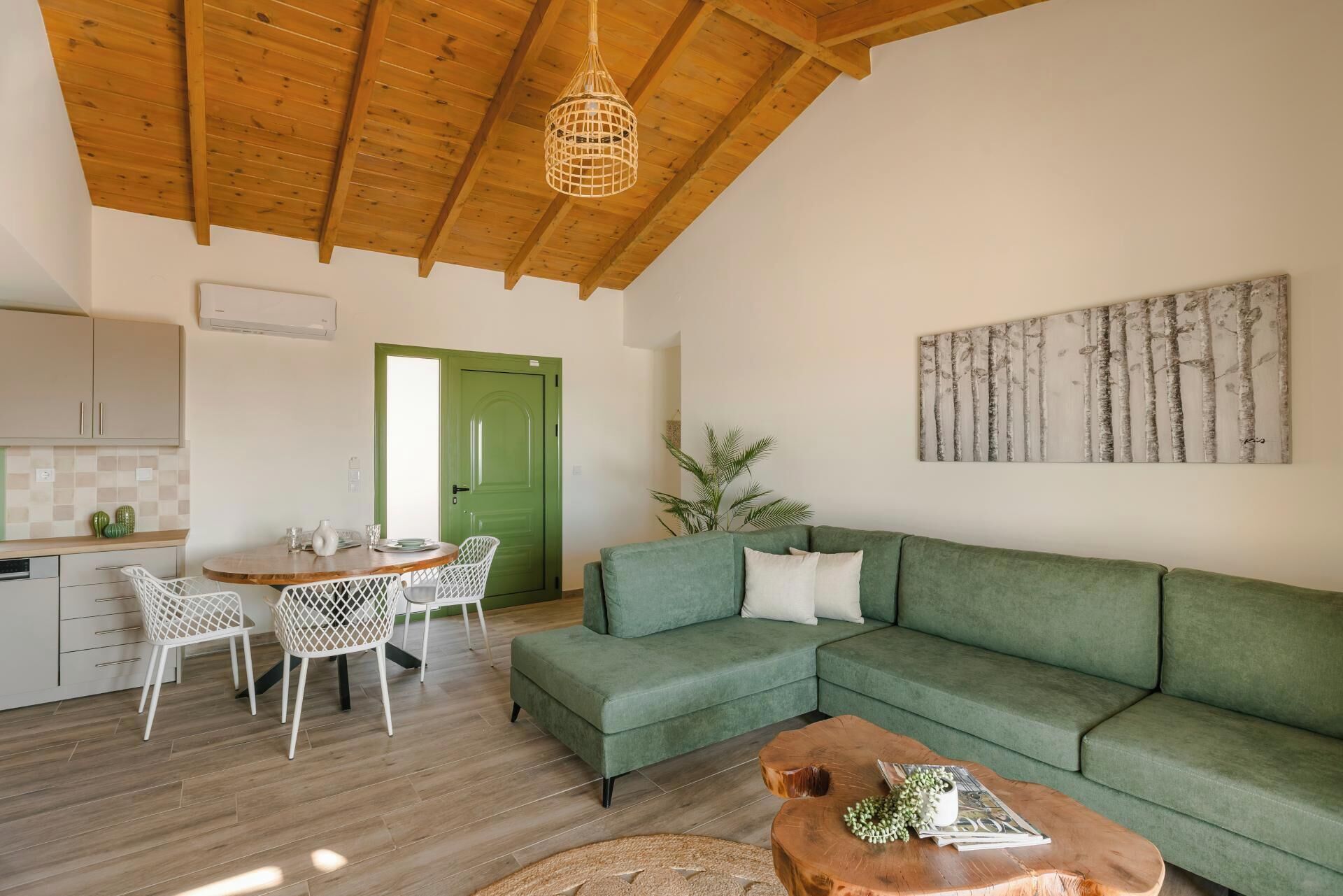 A modern living space with a green sofa, a wooden coffee table, and a dining area with a white table and chairs.