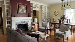 Un salon spacieux doté d’une cheminée, d’un coin repas et d’une bibliothèque remplie de livres et d’objets décoratifs.