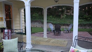 Une terrasse extérieure avec une table en verre, deux chaises et un banc.