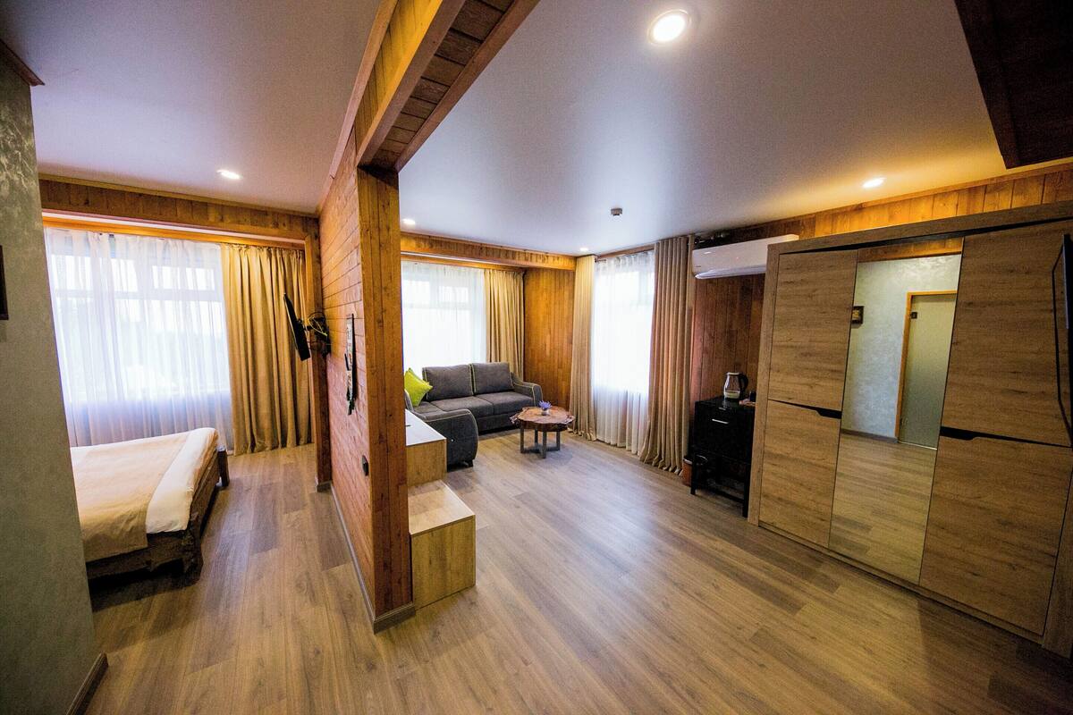 Una habitación con cama, sofá, una mesita y armario empotrado.