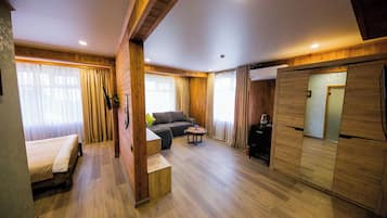 A room with a bed, sofa, small table, and a built-in wardrobe.
