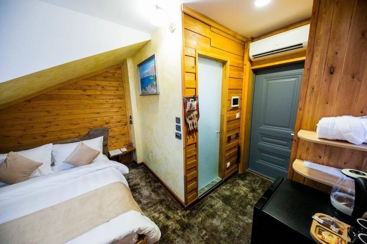 Una habitación pequeña y acogedora con cama, una puerta de madera, una mesita y un estante con toallas.
