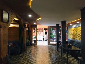 A wooden interior with a herringbone floor, a seating area with tables, and a view into the adjacent room. - Ethno Park Resort (Kok-Jar)