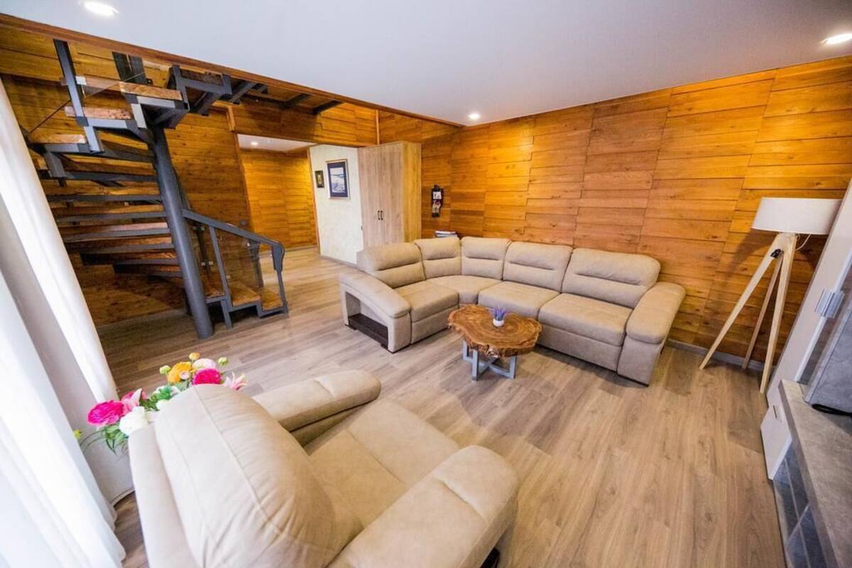 Una sala de estar moderna con un sofá modular, una pared de madera y una escalera espiral.