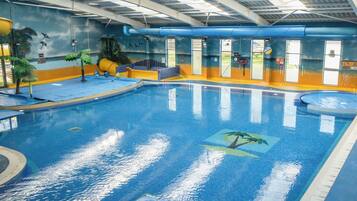 An indoor swimming pool with a mural of tropical scenery, clear water, and a blue ceiling.