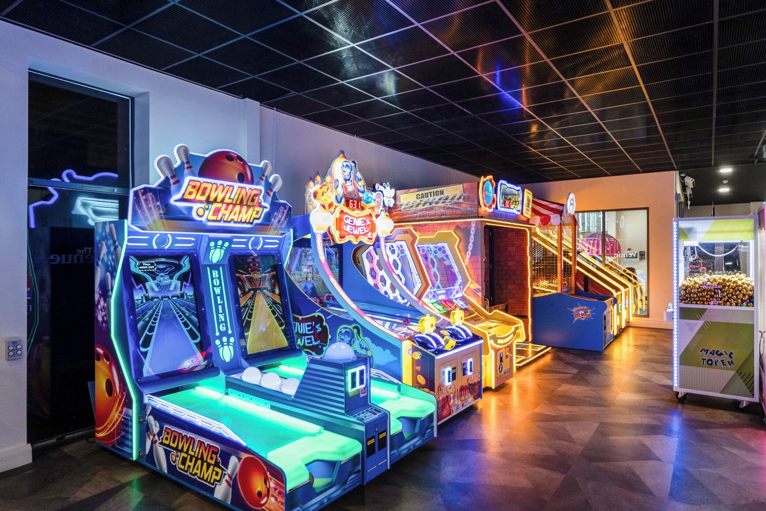 An indoor arcade with neon-lit bowling machines and a caution sign.