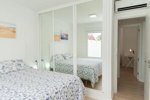 A bedroom with two beds, a large mirror, and a view of the outside. - Bungalow JF/GI by VillaGranCanaria (Comarca Sur)